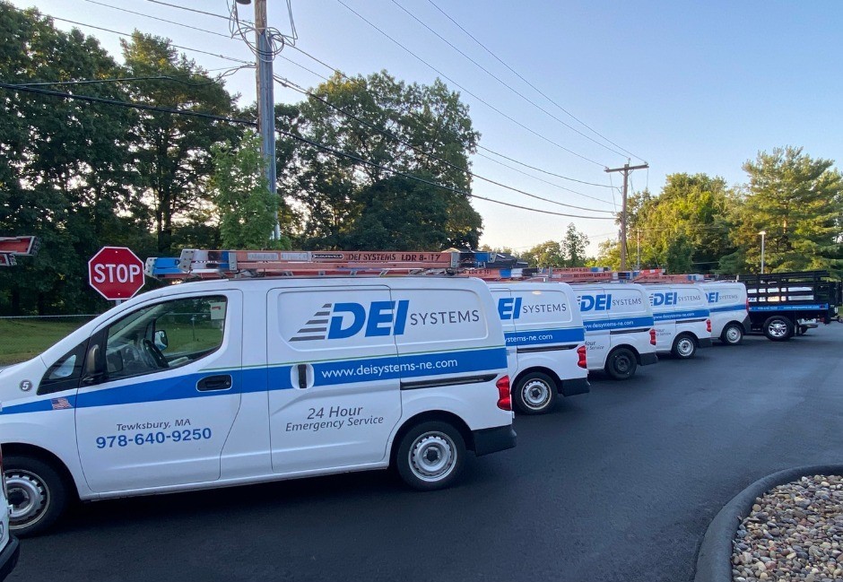 Service Vans A group of DEI Systems 24/7 Service vans parked in a parking lot.