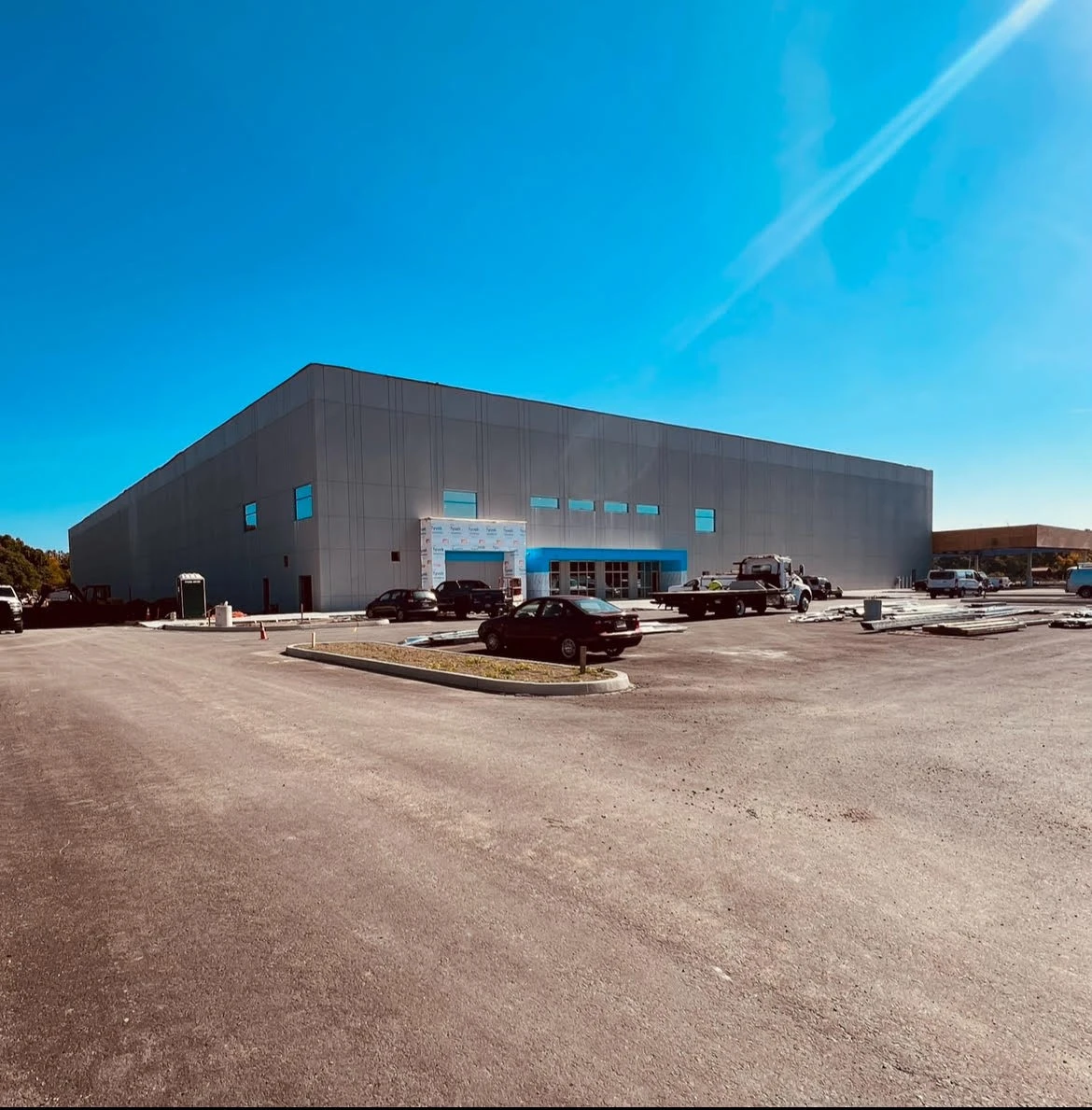 A large warehouse with cars parked in front of it.