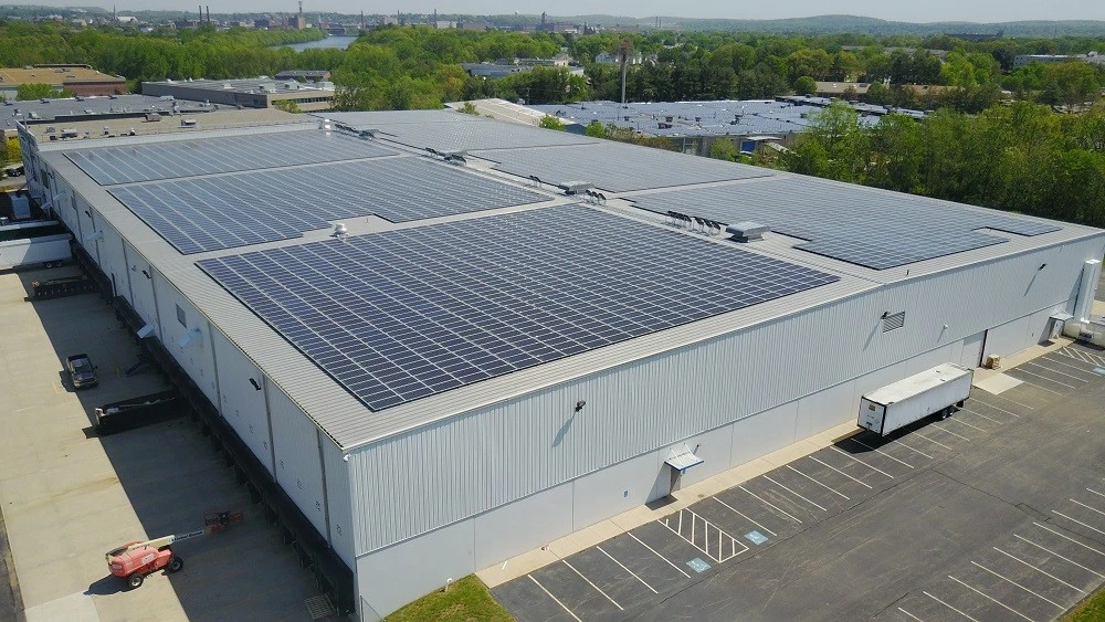 An aerial view of a warehouse with solar panels on the roof.