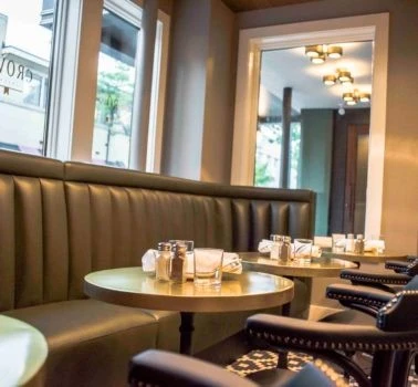 A restaurant with black leather booths and tables.