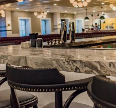 A bar with black stools and a marble counter.