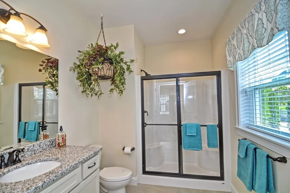 A bathroom with a walk in shower and blue towels.