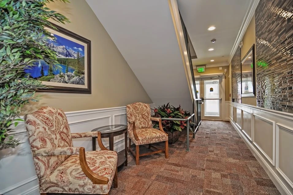 A hallway with two chairs and a fireplace.