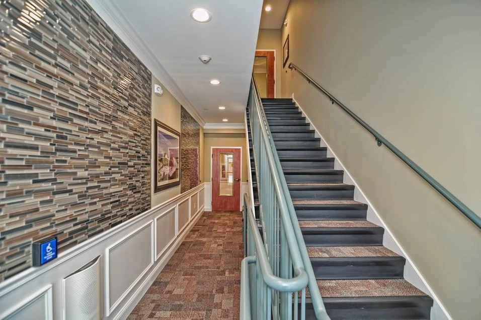 A hallway with stairs and a brick wall.