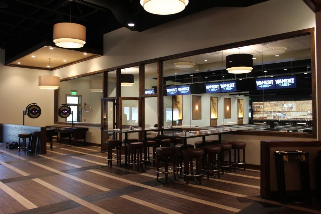 The interior of a bowling alley with tables and chairs.