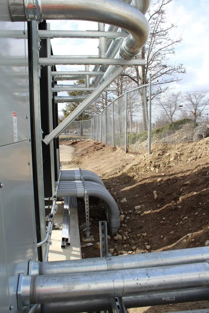 A metal building with pipes and a dirt area.