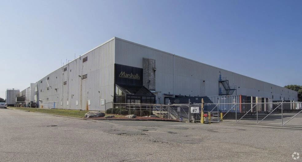 A large warehouse with a fence in front of it.
