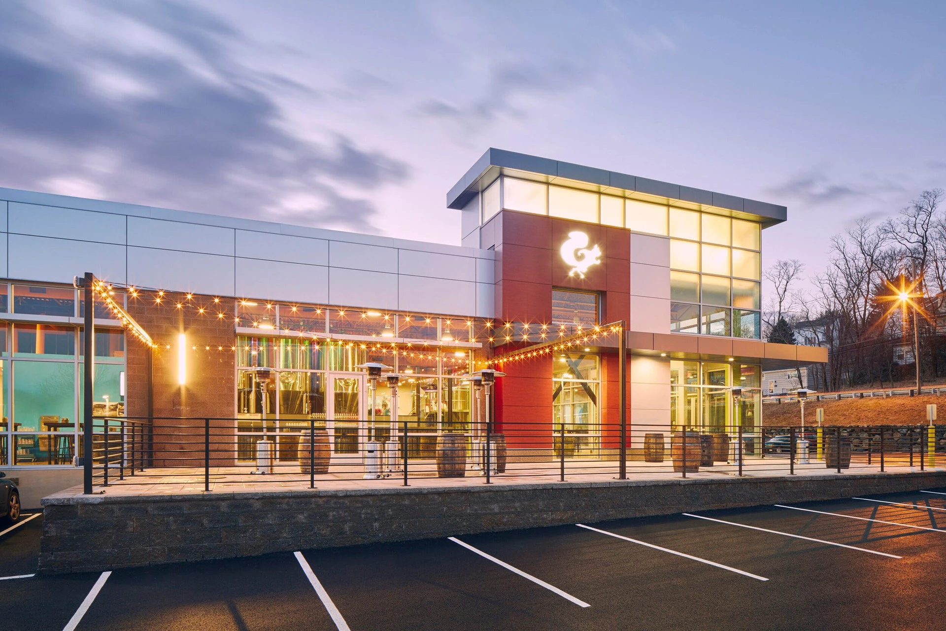 A building with a parking lot at dusk.