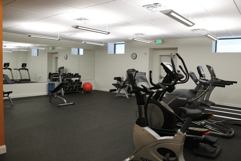 A gym room with a lot of exercise equipment.