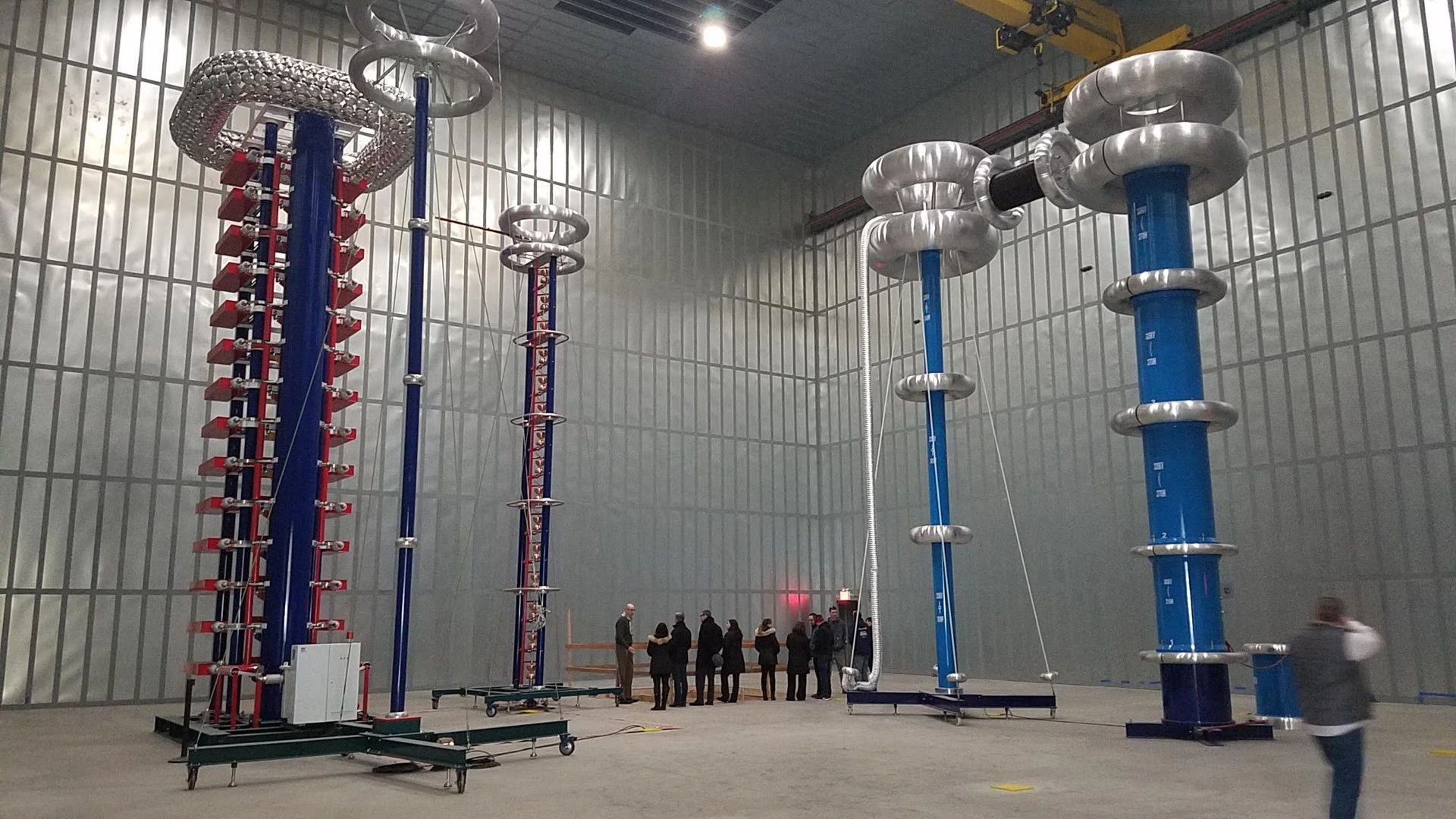 A group of people standing in a large room with several poles.