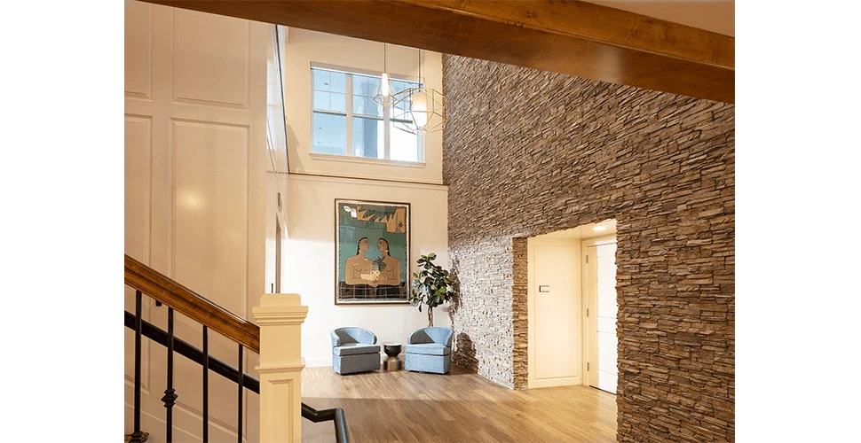 A hallway with a stone wall and a chair.