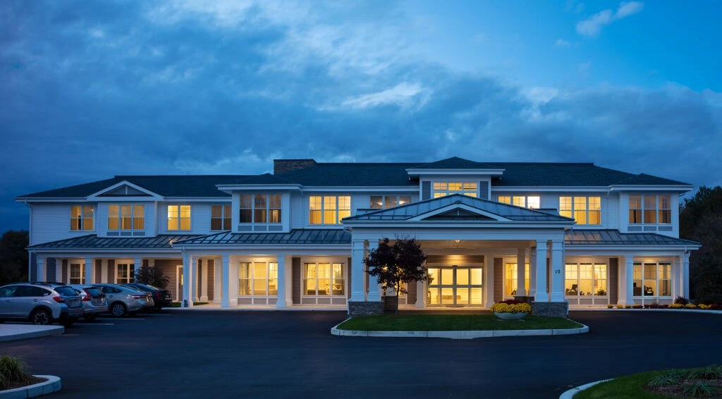 The front of the house is lit up at dusk.