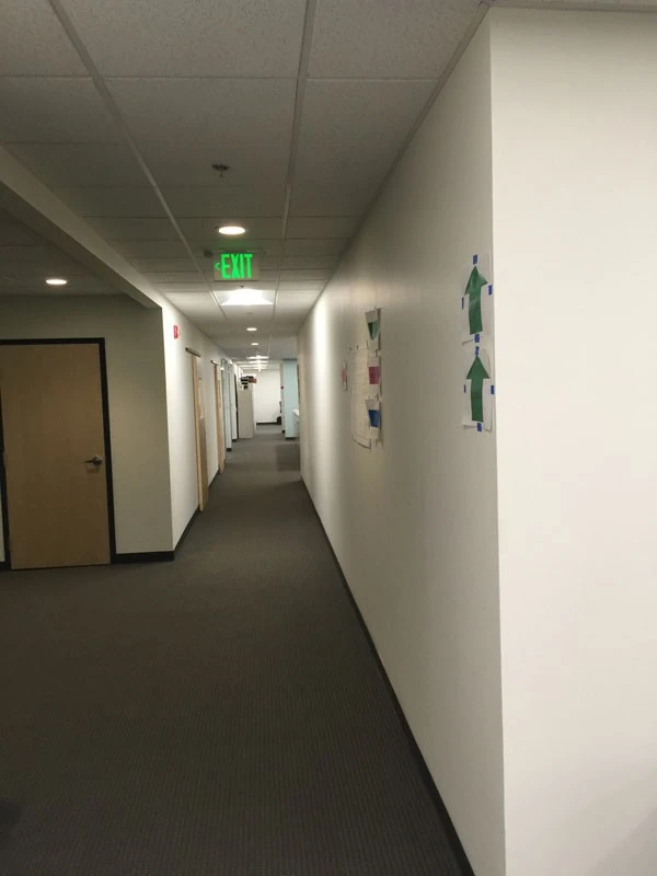 A hallway in an office with a sign on the wall.