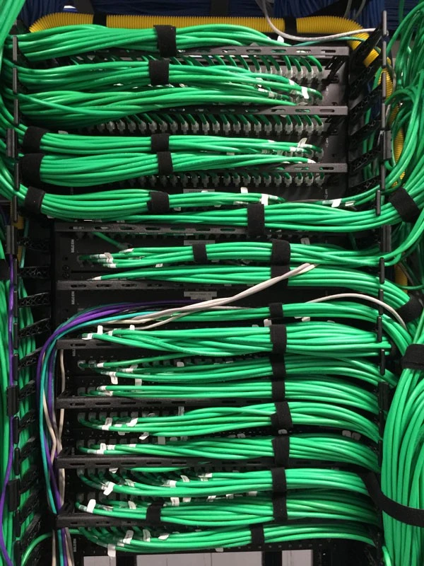 A rack full of green wires in a data center.