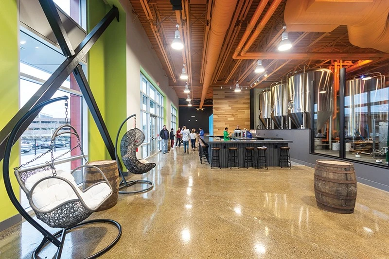 The lobby of a brewery is decorated with chairs and tables.
