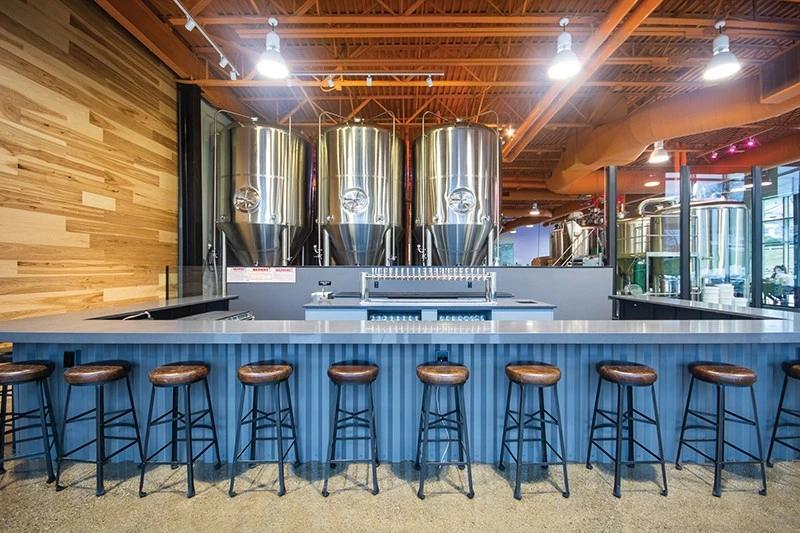 A bar with several stools in a brewery.