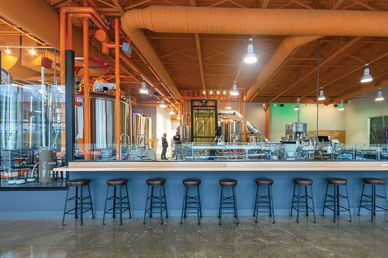 A bar in a brewery with many stools.