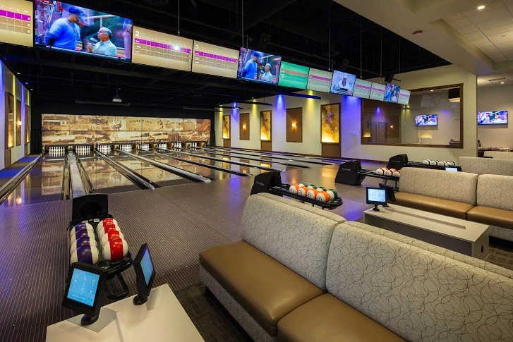 A bowling alley with couches and televisions.