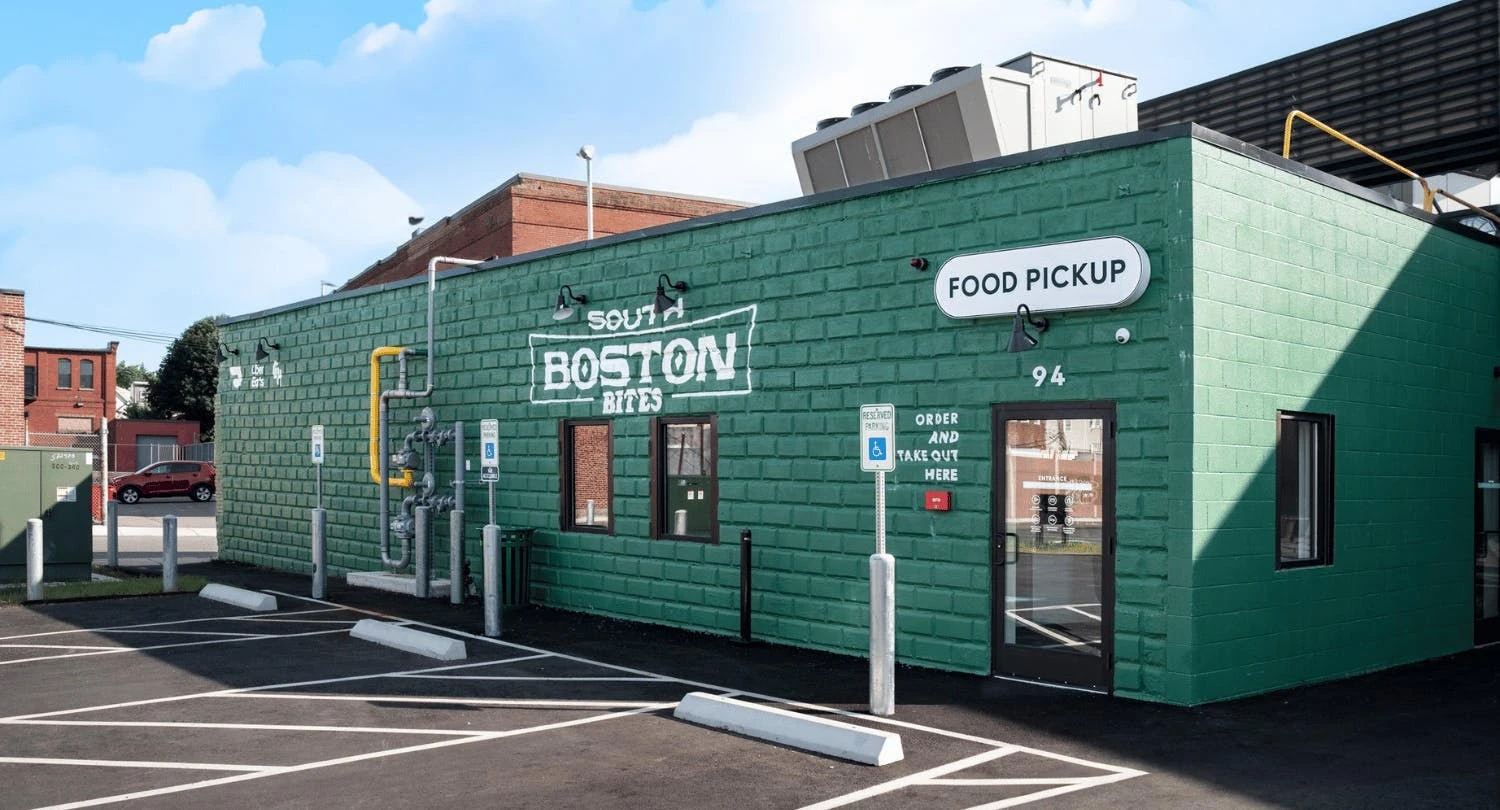 A green building with a parking lot in front of it.