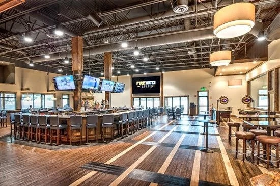 A large bar with wooden floors and stools.