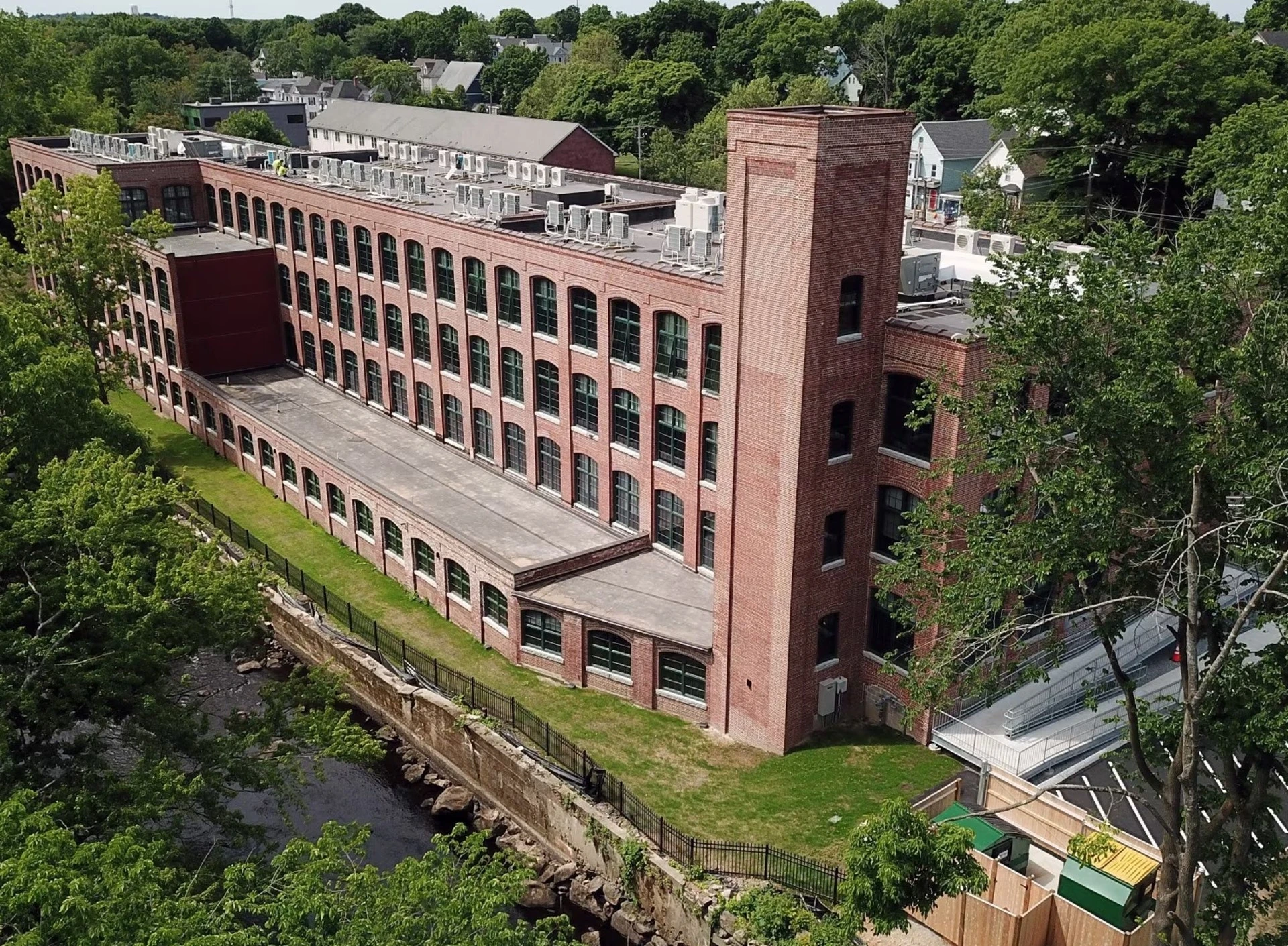 An aerial view of a brick building near a river.