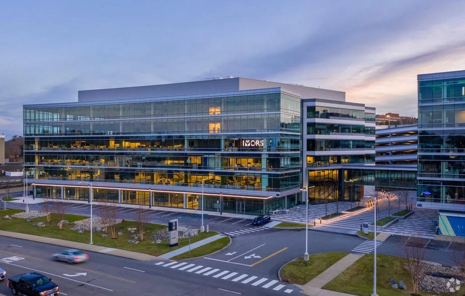 A large glass office building at dusk.