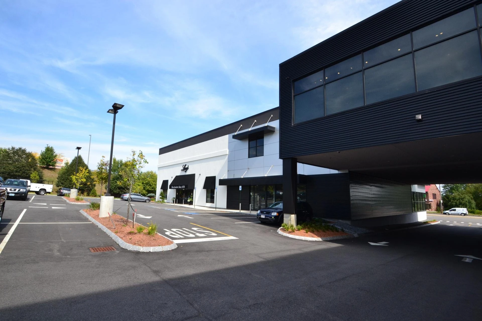 A black and white building with a parking lot.