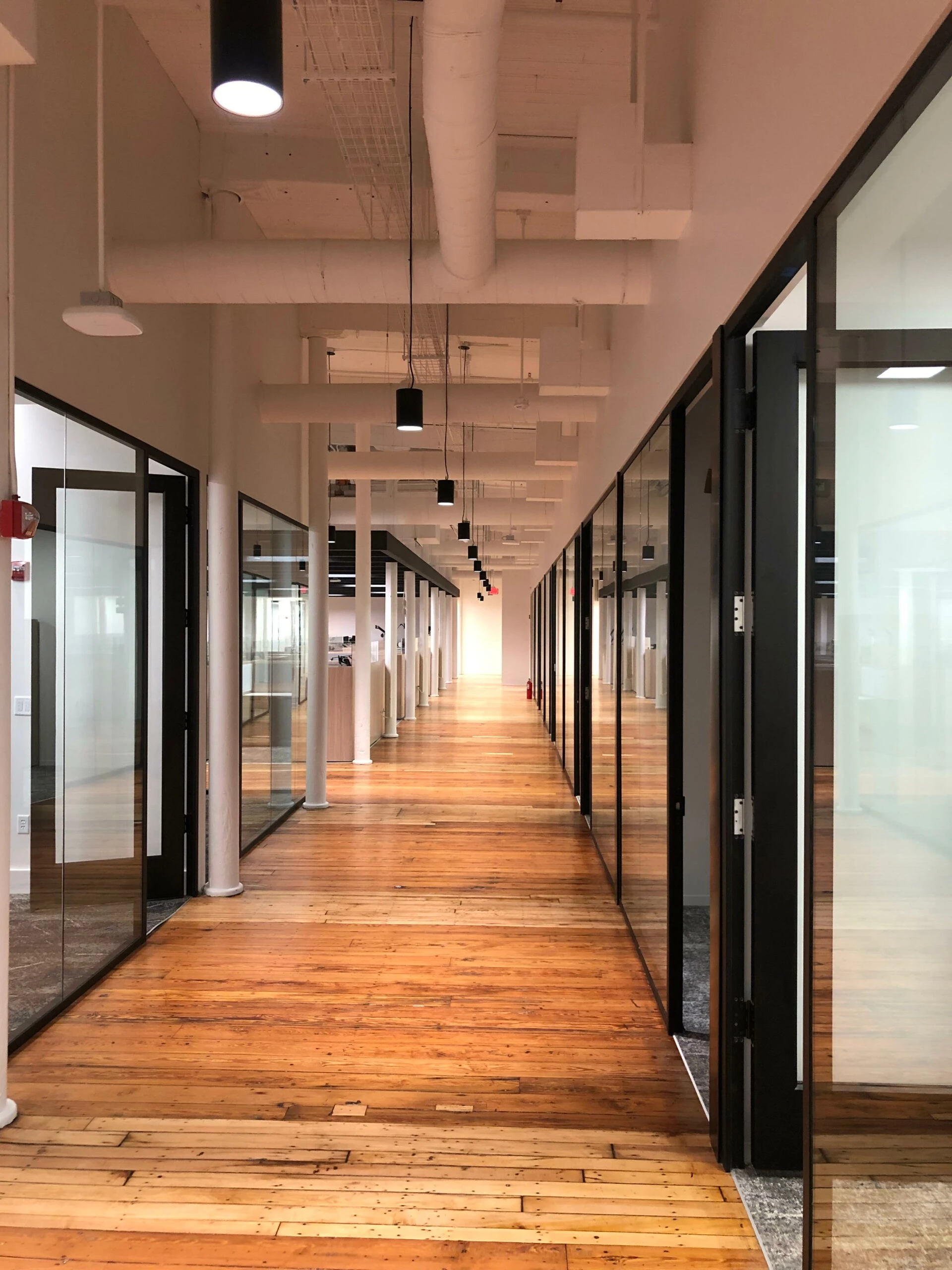A long hallway with glass doors and wooden floors.