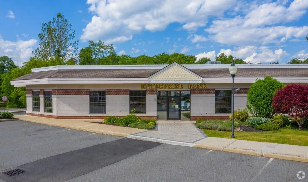 The front of a building with a parking lot and trees.