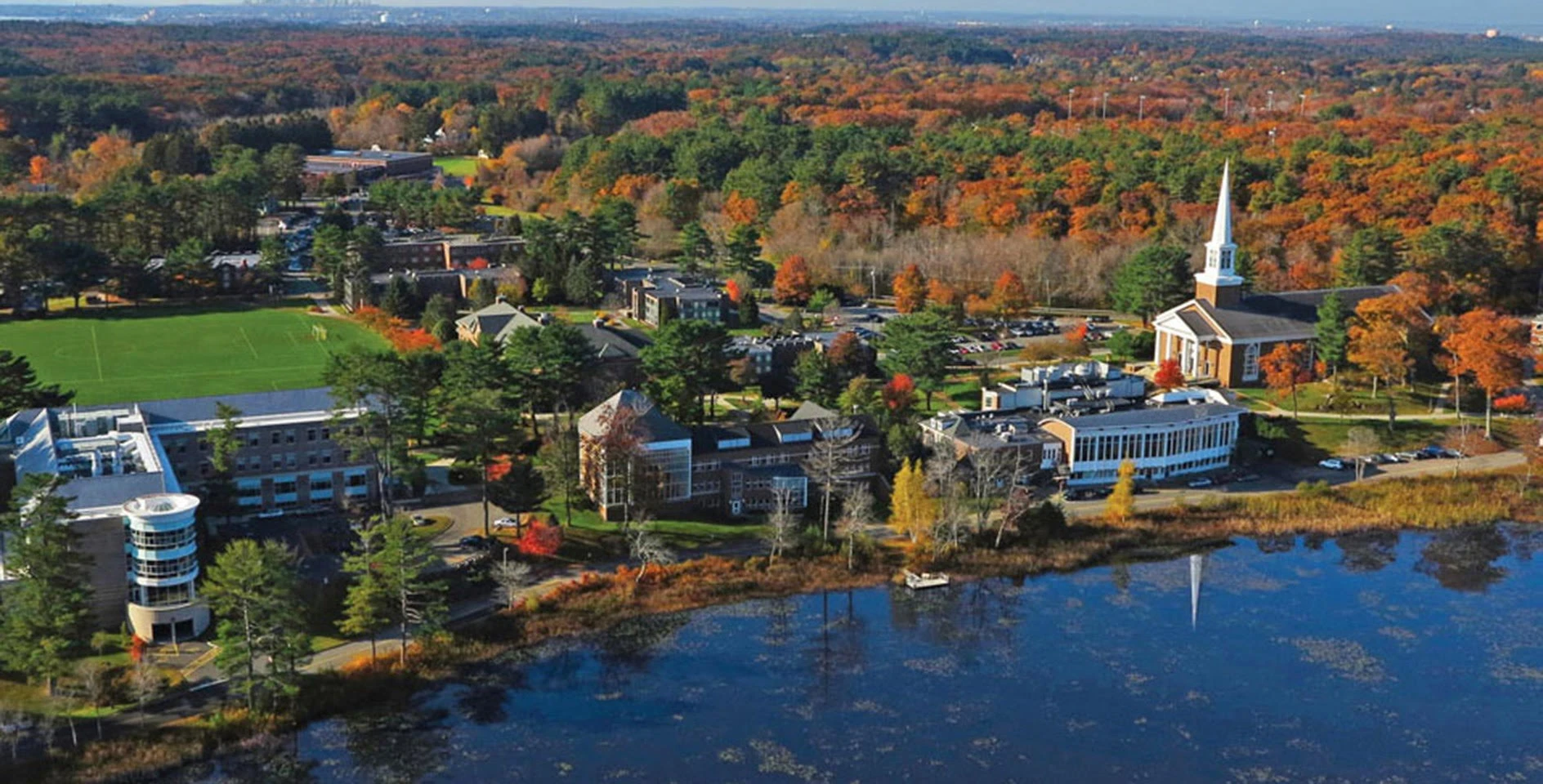 An aerial view of a campus with trees and a lake.