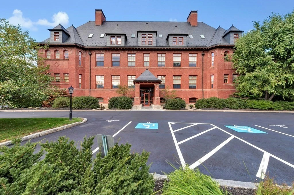 A red brick building with a parking lot in front of it.