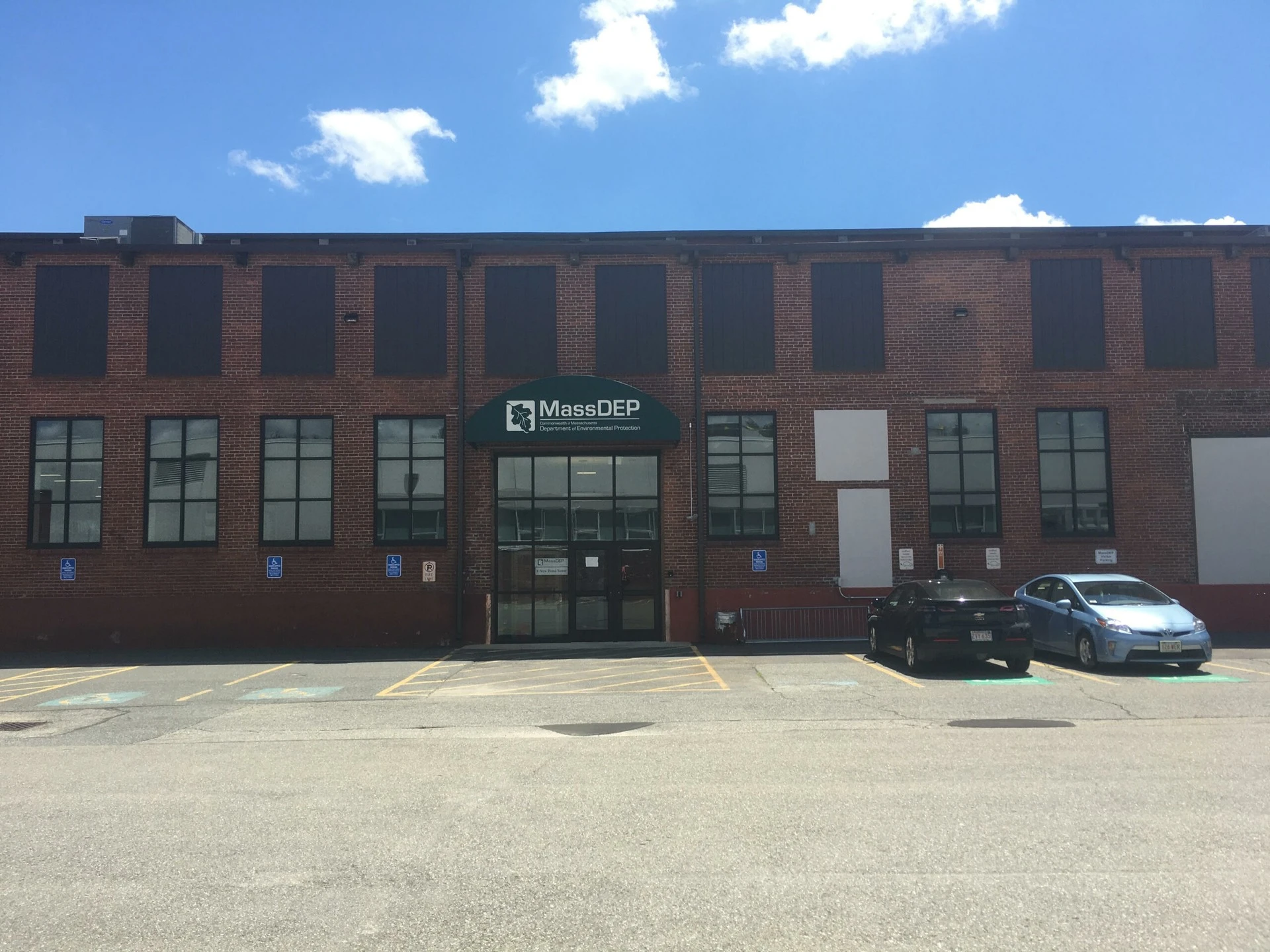 The front of a brick building with cars parked in front of it.